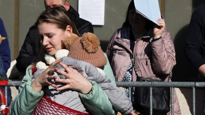 A woman holds a child as people wait outside an immigration office after fleeing from Ukraine to Belgium, following Russia's invasion of Ukraine. (REUTERS)