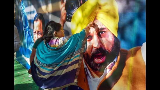 A supporter applies ‘tilak’ on the poster of AAP chief ministerial candidate Bhagwant Mann in celebration of the party’s win in the Punjab assembly elections at the party headquarters in New Delhi on Thursday. (PTI Photo)
