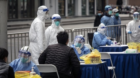 Health workers tests for Covid outside of a clothing market in Shanghai, China.(Bloomberg)