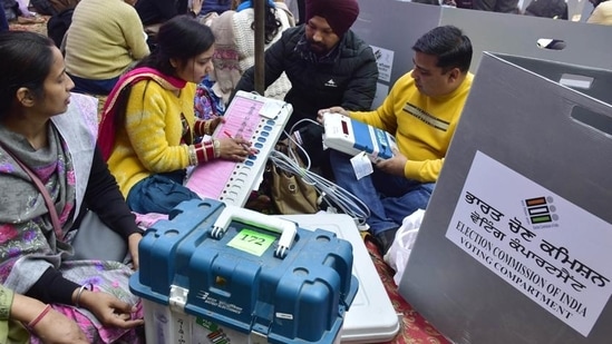Punjab election results 2022: Polling staff examining EVMs and other voting material at a distribution centre on the eve of Punjab elections in Amritsar on Saturday. (Sameer Sehgal/HT)
