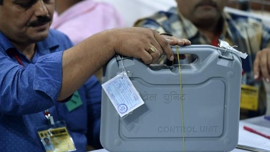 File photo of officials inspecting an Electronic Voting Machine (EVM) during a votes counting process at a booth.(AFP)