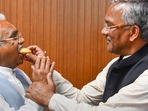 Dehradun: Former Uttarakhand chief minister Trivendra Singh Rawat feeds sweets to BJP State President Madan Kaushik after his victory in the Assembly polls from Haridwar constituency, at the party office, in Dehradun.(PTI)