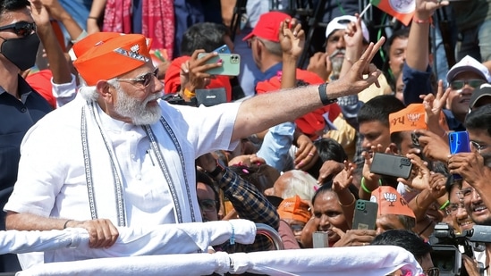 PM Modi waved to people as his roadshow began from the airport to Kamalam, BJP's state headquarters in Gandhinagar.(AFP)