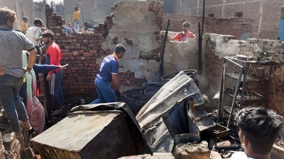 A man salvages belongings from the charred remains his house, after a fire broke out in shanties at Gokulpuri area, in New Delhi. (PTI)