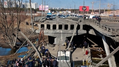 People cross the Irpin river as they evacuate from Irpin town next to a destroyed bridge, amid Russia's invasion of Ukraine, outside of Kyiv, Ukraine. (REUTERS)