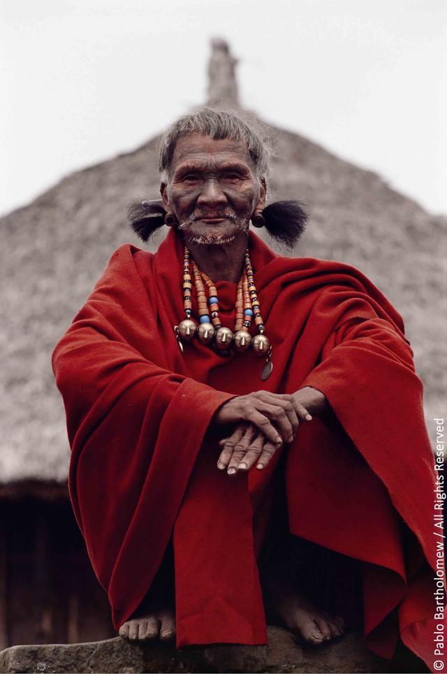 During the 25th anniversary of the founding on the Mon Church in Mon village, the village shaman dressed with his red blanket that is given by the state government to the village elders (Gaon Burra), and wearing earrings of bear hair and a bead necklace with brass heads that signify the number of heads he may have taken in his lifetime. (PABLO BARTHOLOMEW)