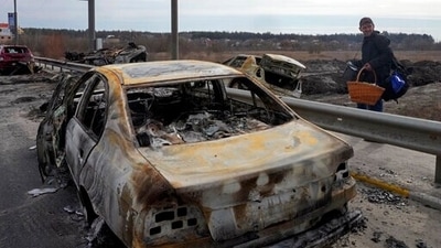 A resident passes by cars burnt in the Russian shellfire as he flees from his hometown on the road towards Kyiv, in the town of Irpin. (AP) A resident passes by cars burnt in the Russian shellfire as he flees from his hometown on the road towards Kyiv, in the town of Irpin. (AP)