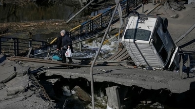 A woman crosses the Irpin river near a destroyed bridge as they evacuate from Irpin town, amid Russia's invasion of Ukraine, outside of Kyiv, Ukraine (REUTERS)