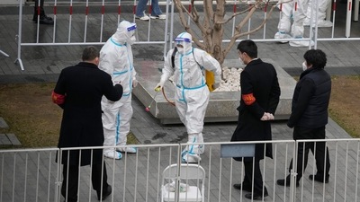 Workers prepare to disinfect visitors at a building closed off after a case of coronavirus was detected in Beijing. (AP) Workers prepare to disinfect visitors at a building closed off after a case of coronavirus was detected in Beijing. (AP)