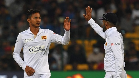 Sri Lanka's Praveen Jayawickrama (L) celebrates with his captain Dimuth Karunaratne after taking the wicket of India's Ravichandran Ashwin (not pictured) during the second day of the second Test cricket match between India and Sri Lanka at the M. Chinnaswamy Stadium in Bangalore on March 13, 2022. (Photo by Manjunath KIRAN / AFP) / ----IMAGE RESTRICTED TO EDITORIAL USE - STRICTLY NO COMMERCIAL USE-----(AFP)