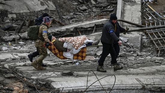 Ukrainian servicemen evacuate an elderly woman on a stretcher from the city of Irpin on March 13, 2022. - Russian forces advance ever closer to the capital from the north, west and northeast.(AFP)