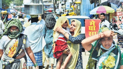Pedestrians shield themselves by covering their heads during a blazing hot and humid climate as the mercury soars in the city on Monday. (Praful Gangurde/HT Photo)
