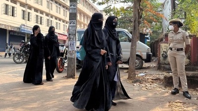 Hijab-wearing students arrive to attend classes as a policewoman stands guard outside a government girls school after the recent hijab ban, in Udupi town in Karnataka. (File photo - Reuters)