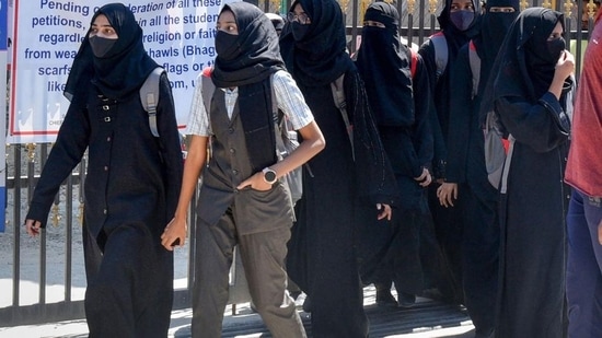 Students walk back home after being denied entry with hijab at a college in Shivamogga on February 28.(PTI)