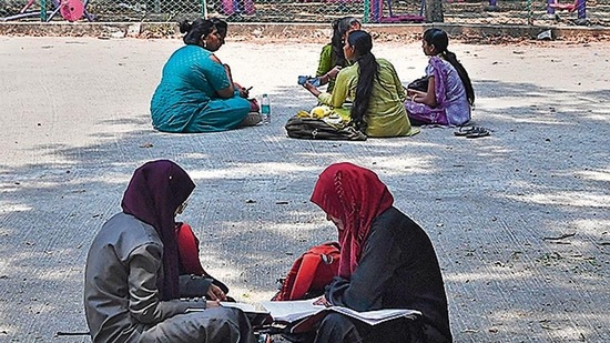 Students sit and study in the playground of a college in Bangalore on March 15, 2022, after an Indian court upheld a local ban on the hijab in classrooms, weeks after the edict stoked violent protests and renewed fears of discrimination against the country's Muslim minority. (Photo by Manjunath Kiran / AFP)
