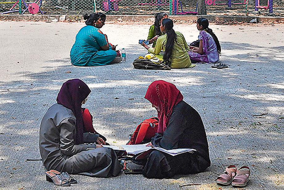Students sit and study in the playground of a college in Bangalore on March 15, 2022, after an Indian court upheld a local ban on the hijab in classrooms, weeks after the edict stoked violent protests and renewed fears of discrimination against the country's Muslim minority. (Photo by Manjunath Kiran / AFP)