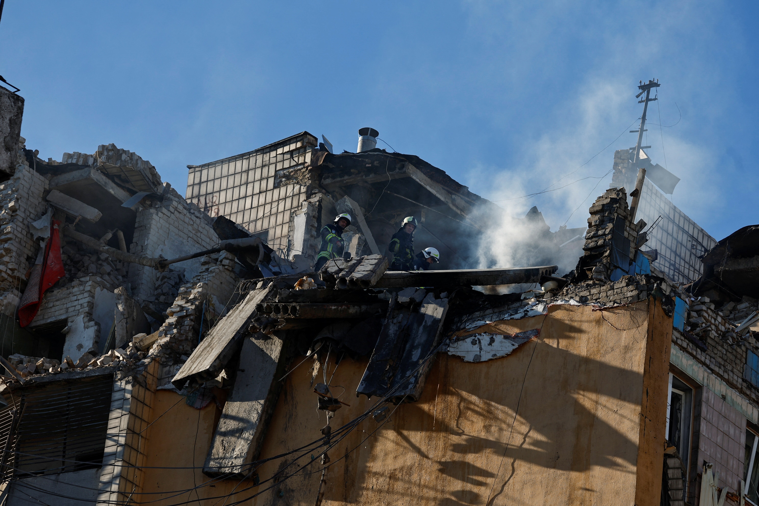 Rescuers work atop an apartment building that was hit by shelling, as Russia's invasion on Ukraine continues, in Kyiv, Ukraine. (REUTERS)