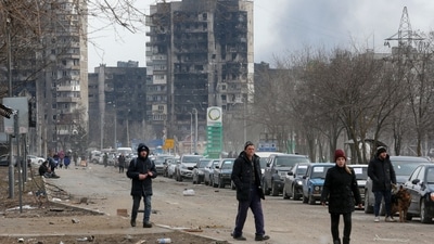 A view shows people and a line of cars near blocks of flats destroyed during Ukraine-Russia conflict, as evacuees leave the besieged southern port city of Mariupol. (REUTERS)