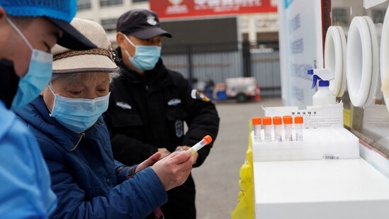 A woman holds a sample tube before getting tested for Covid-19 at a mobile nucleic acid testing site on a street in Beijing, China on March 17, 2022.(Reuters)