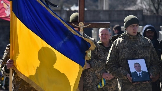 Members of the Ukrainian military carry a Ukrainian flag and picture of Major Ivan Skrypnyk, who died as a result of Russia's missile attack on the Ukrainian military base in Yavoriv.(REUTERS)