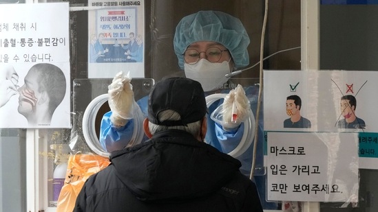 A medical worker in a booth prepares to take a nasal swab sample from a man at a makeshift testing site in Seoul, South Korea on March 17, 2022. (AP Photo) A medical worker in a booth prepares to take a nasal swab sample from a man at a makeshift testing site in Seoul, South Korea on March 17, 2022. (AP Photo)