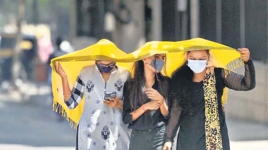 Young girls shield themselves by covering their heads in the afternoon from severe scorching heat at Mulund on Tuesday. (Satish Bate/HT PHOTO)