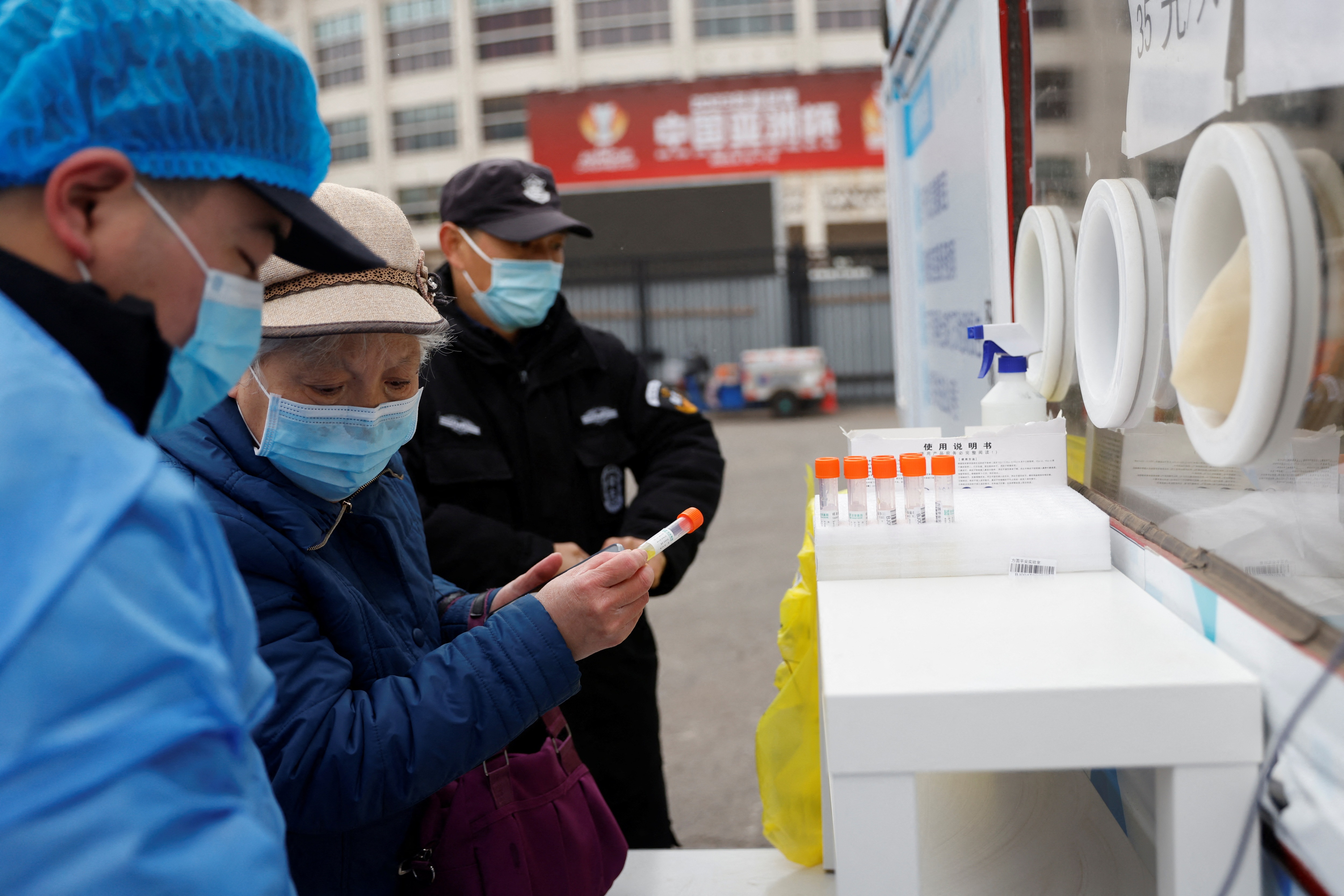 A woman holds a sample tube before getting tested for Covid-19 at a mobile nucleic acid testing site on a street in Beijing, China on March 17, 2022. (Reuters)