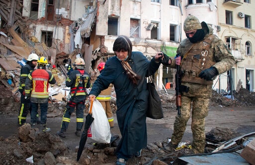 A volunteer of the Ukrainian Territorial Defense Forces assists a woman to cross the street in Kharkiv, Ukraine on March 16, 2022. (AP Photo) A volunteer of the Ukrainian Territorial Defense Forces assists a woman to cross the street in Kharkiv, Ukraine on March 16, 2022. (AP Photo)