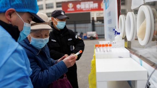 A woman holds a sample tube before getting tested for Covid-19 at a mobile nucleic acid testing site on a street in Beijing, China on Thursday.(Reuters)