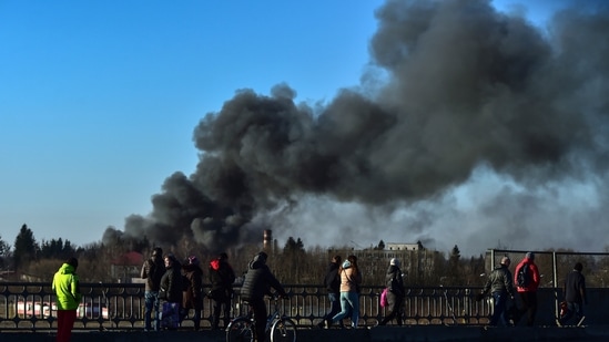 People walk as a cloud of smoke raises after an explosion near the airport, in Lviv, western Ukraine(AP) People walk as a cloud of smoke raises after an explosion near the airport, in Lviv, western Ukraine(AP)