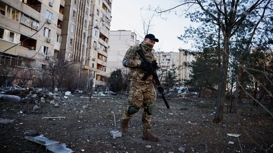 Seorang anggota militer Ukraina mengamati area di sebelah bangunan tempat tinggal yang terkena rudal yang dicegat, saat invasi Rusia ke Ukraina berlanjut, di Kyiv, (REUTERS)