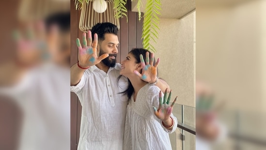 This is Mouni Roy's first Holi with her husband Suraj Nambiar after their marriage. Dressed in all-white attire, the Gold actor and her significant other posed for the camera with colourful hands and lost in each other's eyes.(Instagram/@imouniroy)