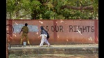 A hijab-wearing student walks past a worker painting a wall to conceal a pro-hijab slogan, Hospet, March 16, 2022 (PTI) A hijab-wearing student walks past a worker painting a wall to conceal a pro-hijab slogan, Hospet, March 16, 2022 (PTI)