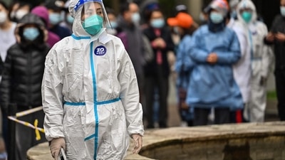 A worker wearing protective gear looks on as people wait to be tested for the Covid-19 coronavirus at a residential compound in Shanghai. (AFP) A worker wearing protective gear looks on as people wait to be tested for the Covid-19 coronavirus at a residential compound in Shanghai. (AFP)
