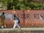 A hijab-wearing student walks past a worker painting a wall to conceal a pro-hijab slogan, Hospet, March 16, 2022 (PTI)(HT_PRINT) A hijab-wearing student walks past a worker painting a wall to conceal a pro-hijab slogan, Hospet, March 16, 2022 (PTI)(HT_PRINT)