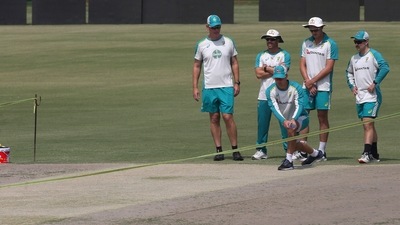 Australia's skipper Pat Cummins and teammates examine the pitch prior to attend a practice session at the Gaddafi Stadium (AP) Australia's skipper Pat Cummins and teammates examine the pitch prior to attend a practice session at the Gaddafi Stadium (AP)