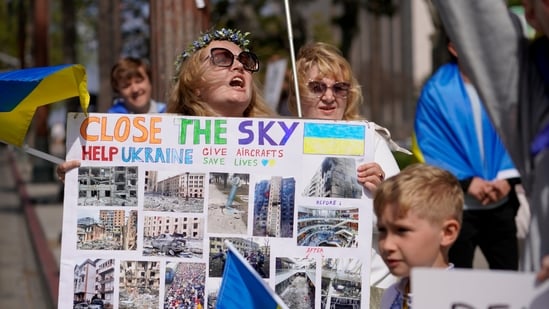A Ukrainian woman holds a sign with news images showing the damage done to Ukraine by Russia's invasion of the country during a rally in Los Angeles on Saturday, March 19, 2022. (AP Photo/Damian Dovarganes)