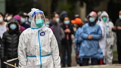 A worker wearing protective gear looks on as people wait to be tested for the Covid-19 coronavirus at a residential compound in Shanghai. (AFP) A worker wearing protective gear looks on as people wait to be tested for the Covid-19 coronavirus at a residential compound in Shanghai. (AFP)