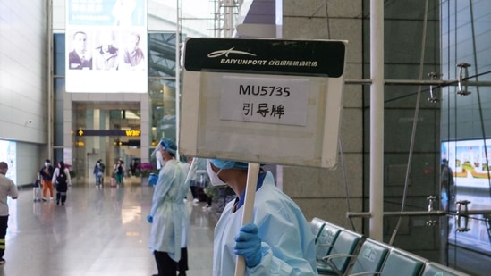 A staff member holds up a board to guide relatives of passengers on China Eastern flight MU5375 after it failed to arrive at Guangzhou Baiyun International Airport in China's southern Guangdong province on March 21, 2022.&nbsp;(AFP)