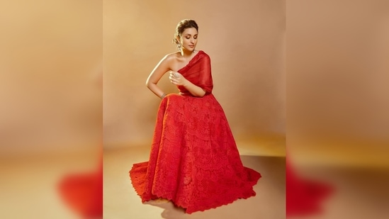 The top part of the outfit has an extra red material stitched asymmetrically while the flared portion is filled with intricate embroidery work.(Instagram/@parineetichopra)