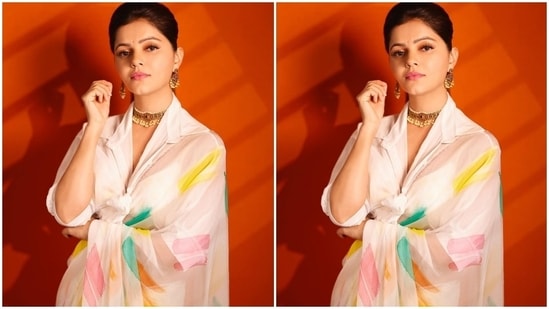 Rubina's saree features colourful geometric prints in yellow, green, orange, and pink hues. She draped it around her body in traditional style and chose a shirt blouse to round it all off. The blouse comes with wide collars, folded sleeves, midriff-baring cropped hem, plunging neckline and a front knot.(Instagram/@rubinadilaik)