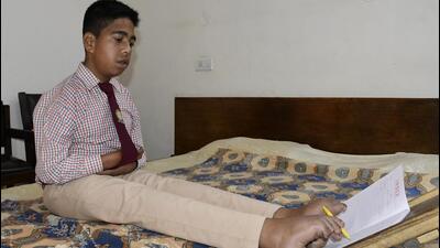 Kamaljit Singh, a specially abled student, cannot use his arms and hands, but still managed to score 57% in his Class 9 exams by writing with his feat. (Harsimar Pal Singh/HT)