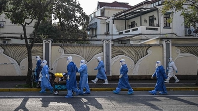 Health workers wearing protective gear walk to a compound to test residents for the Covid-19 coronavirus in Shanghai. (AFP)
