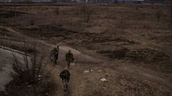 Soldiers walk on a path as smoke billows from the town of Irpin, on the outskirts of Kyiv, Ukraine.