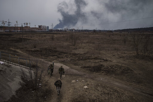 Soldiers walk on a path as smoke billows from the town of Irpin, on the outskirts of Kyiv, Ukraine. (AP file photo)