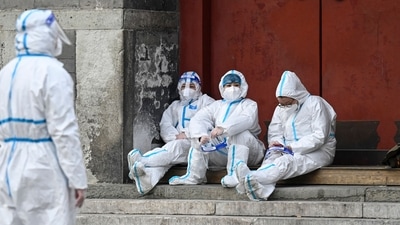 Health workers in protective gear sit by steps at a makeshift Covid-19 testing site near Drum Tower in Beijing. (AFP file photo) Health workers in protective gear sit by steps at a makeshift Covid-19 testing site near Drum Tower in Beijing. (AFP file photo)