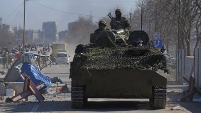 Service members of pro-Russian troops in uniform without insignia drive an armoured vehicle in the besieged southern port city of Mariupol, Ukraine. (REUTERS)