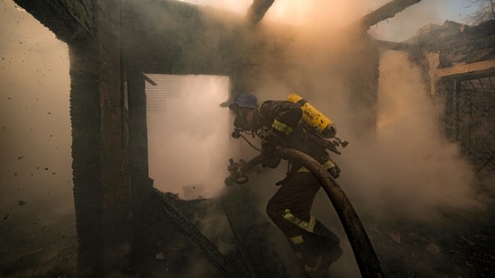 A Ukrainian firefighter sprays water inside a house destroyed by shelling in Kyiv, Ukraine, Wednesday.&nbsp;