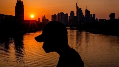 A man wears a face mask as he walks on a bridge over the river Main as the sun sets in Frankfurt, Germany, Thursday, March 24, 2022. (AP Photo/Michael Probst) (AP)