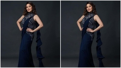 Madhuri’s saree came with a shimmery halter neck long blouse and a swirl throw. The midnight blue saree perfectly hugged her shape and complemented her curves. (Instagram/@gauravguptaofficial)